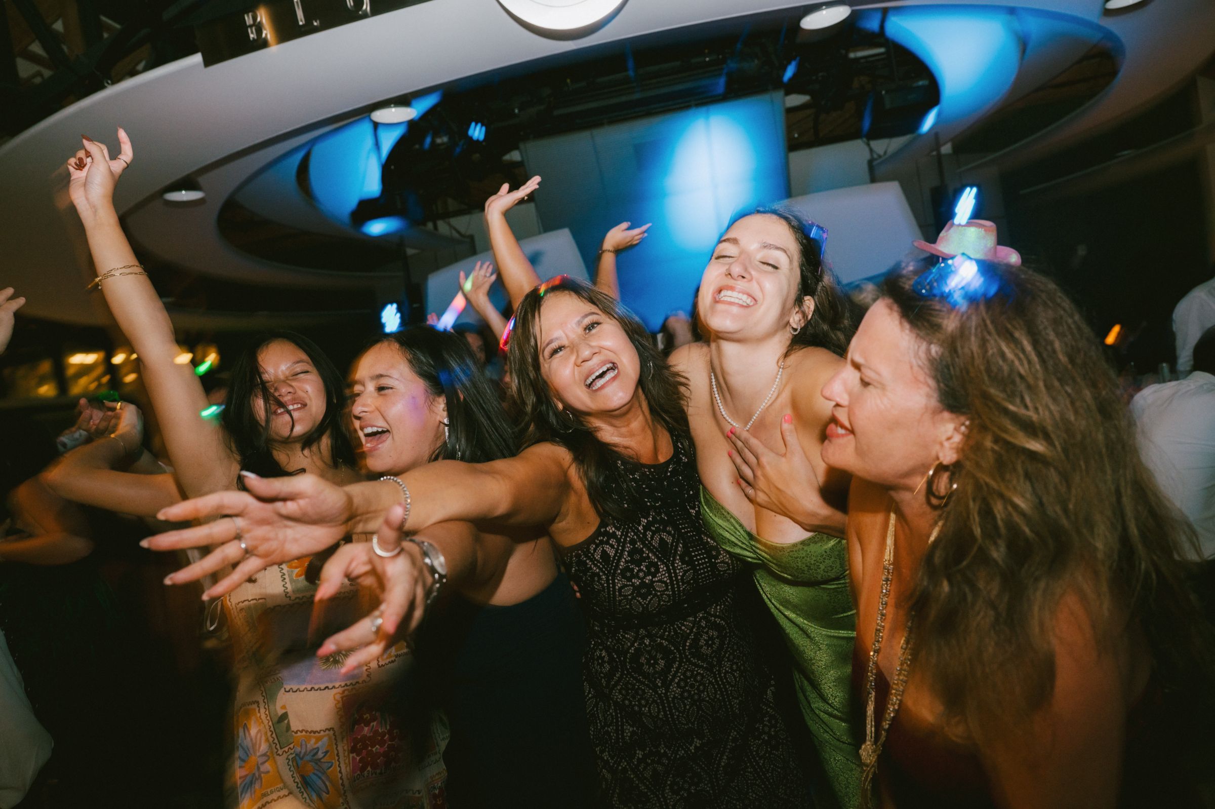 Guests dancing with their arms out under blue light at a north Georgia wedding reception