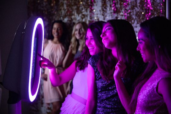 Guests tapping the Nightbird Social Booth screen while their friends wait to jump in