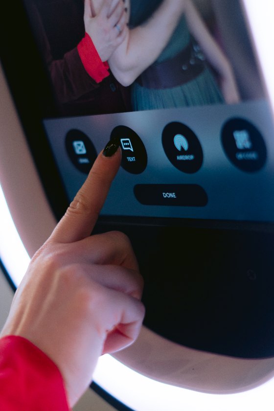 A guest tapping the text-message button on the booth screen to send the photo to her phone