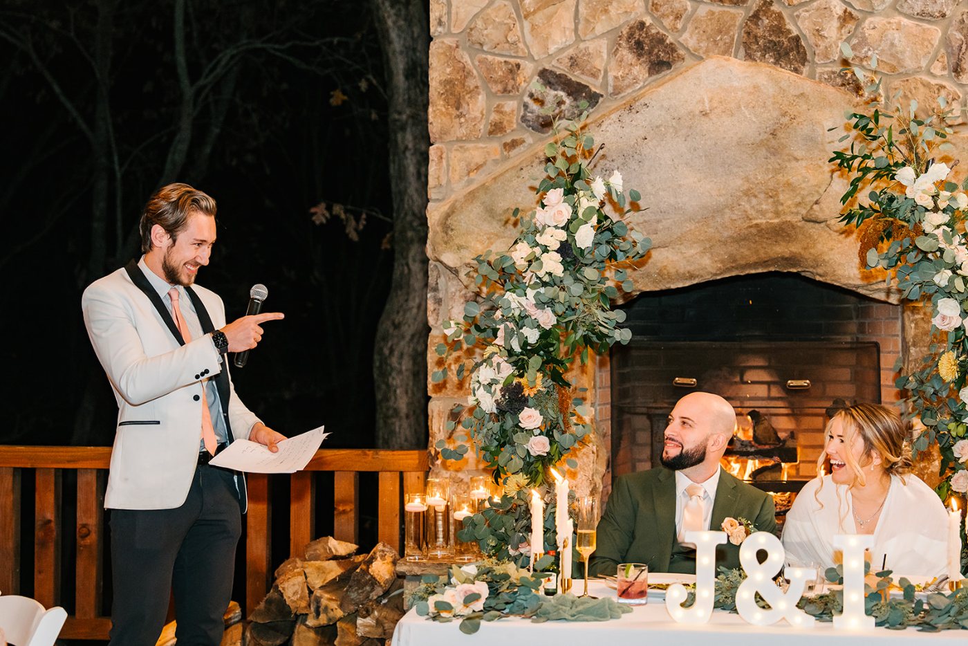A Nightbird DJ in a white dinner jacket on the microphone beside the couple at their reception